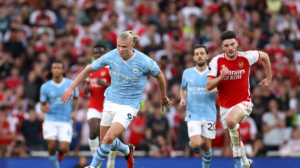 Erling Haaland in light blue Manchester City jersey runs with the ball